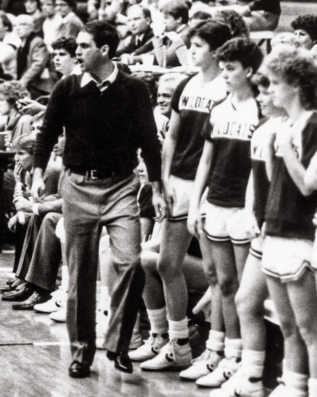 In a packed stadium, coach and four female players watching a Villanova Women’s Basketball game from the sidelines