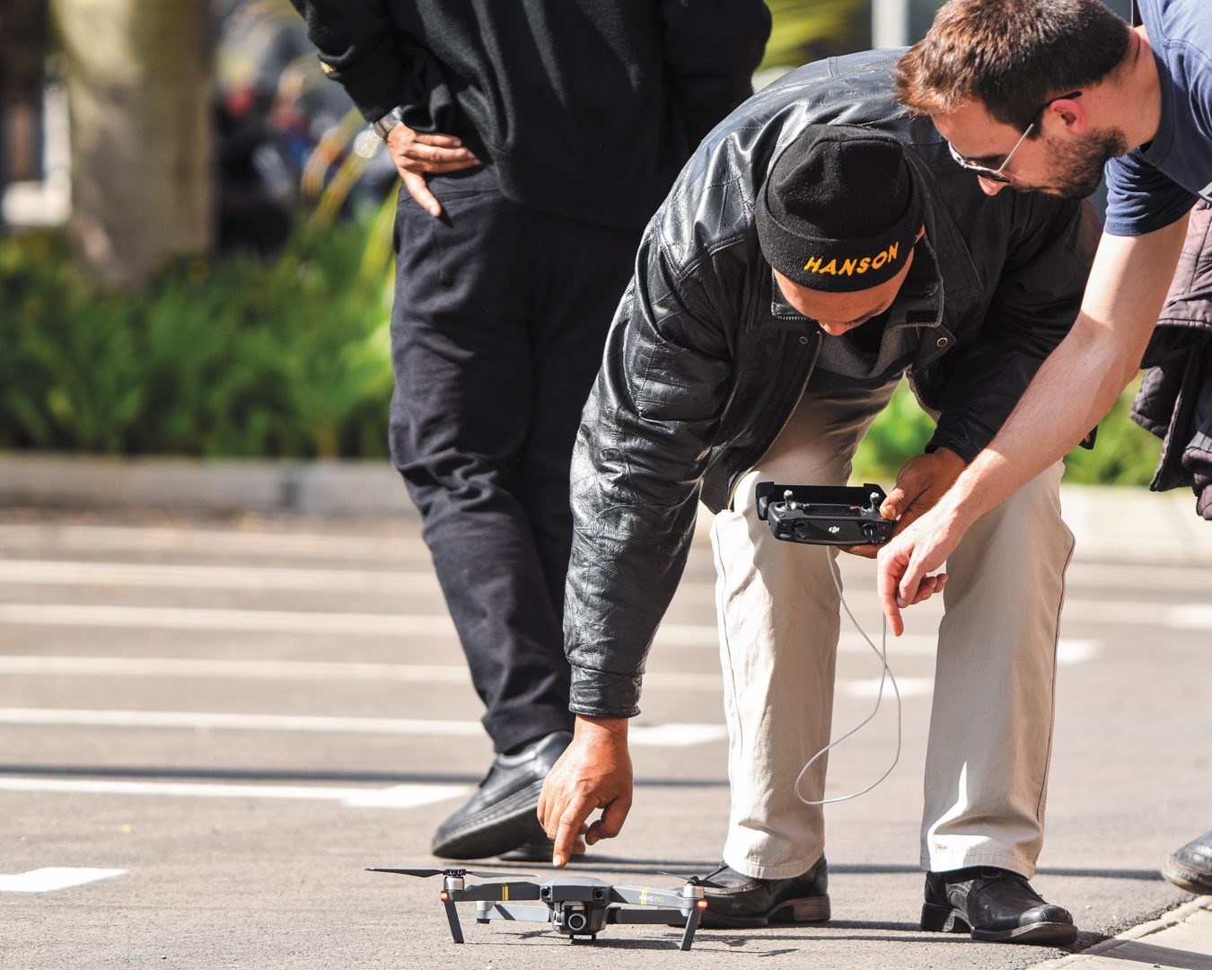 In a parking lot in Madagascar, a CRS staff person bends over a drone as Eric Wagner trains him to launch it