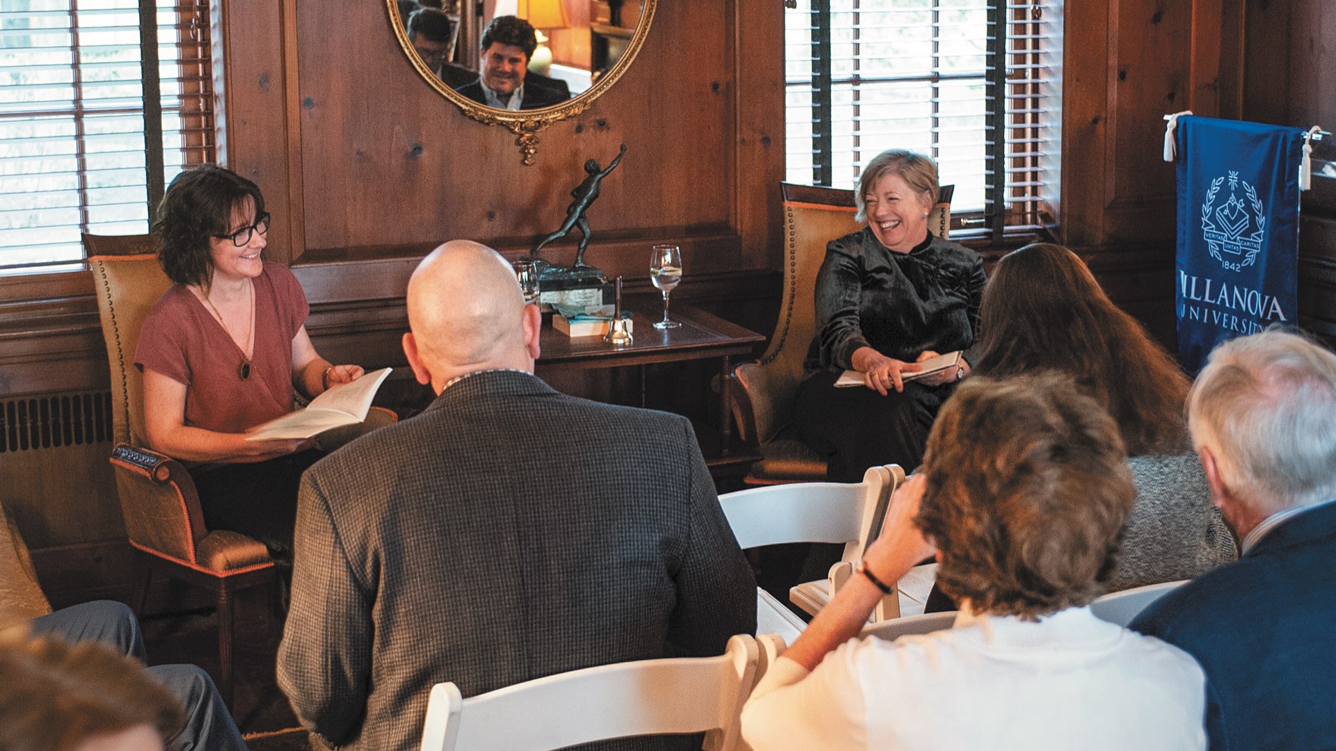 Irish poets Colette Bryce and Vona Groarke in a wood-paneled room in the Kelly House laughing and reading to an audience