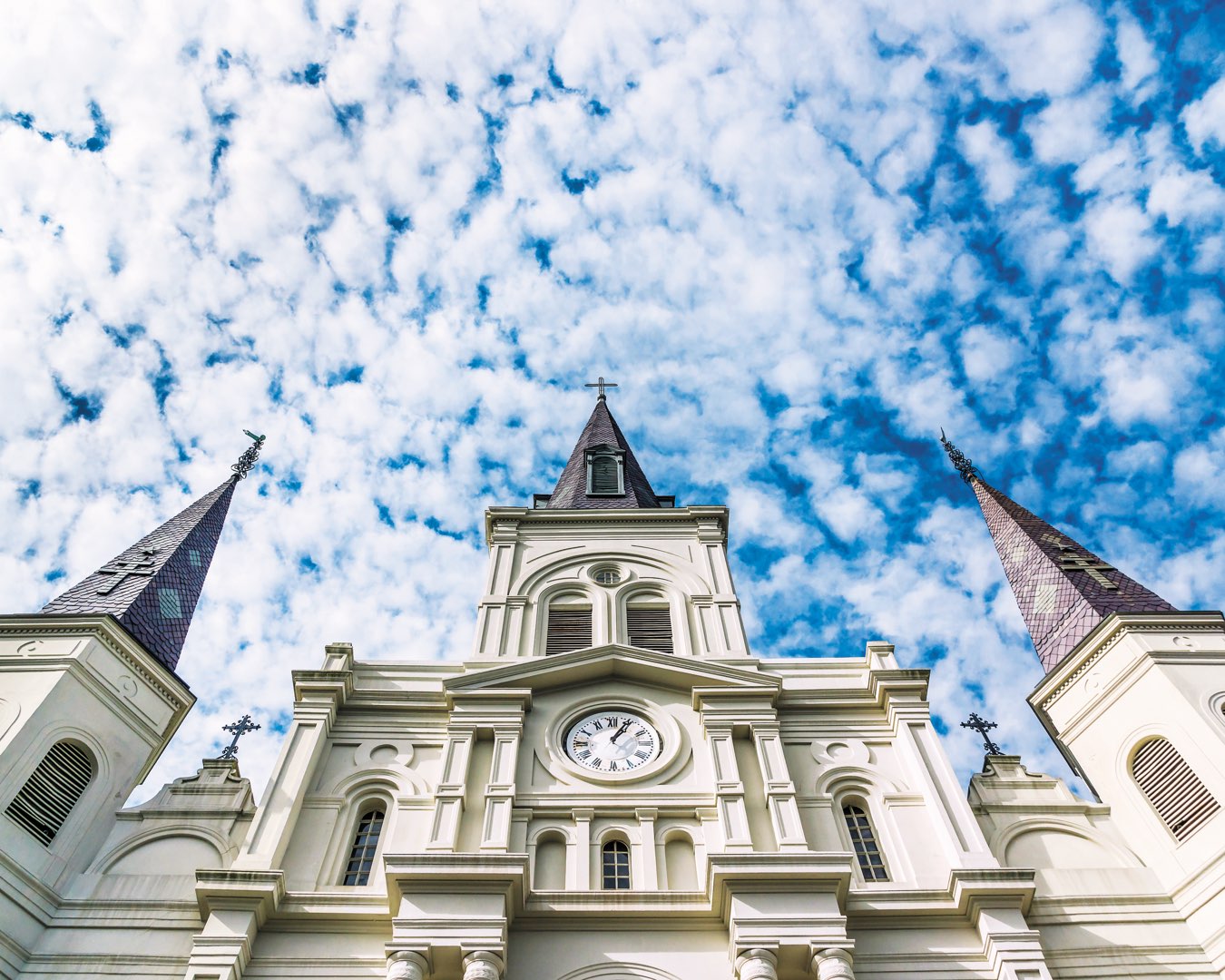 Close-up of the iconic clock tower of Saint Louis Cathedral in New Orleans, Louisiana against a bright blue sky