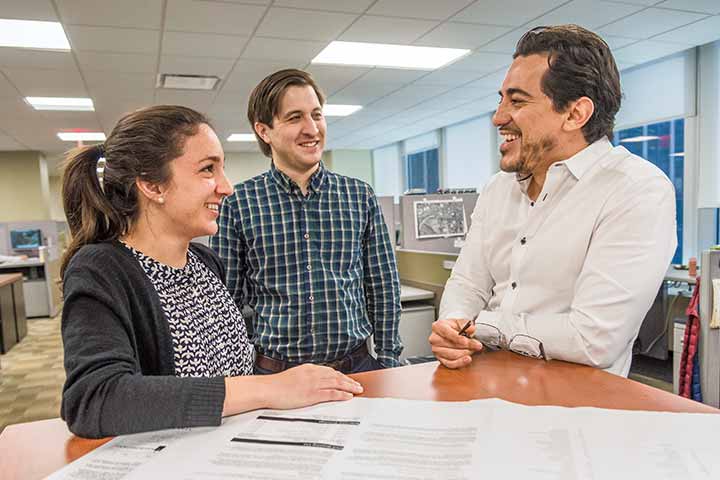 Dina Ferraiuolo standing with two male colleagues in an office setting