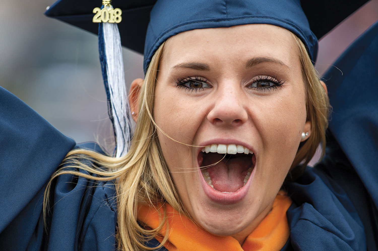 Female Villanova student wearing a graduation robe and celebrating.