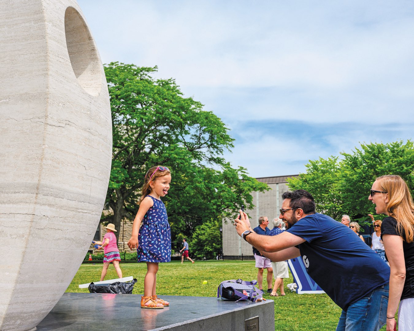 Alumnus at Reunion taking a picture of young daughter in front of the Oreo