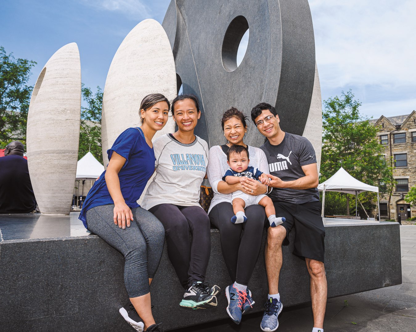 Four alums post with a baby in a wildcats shirt in front of the Oreo