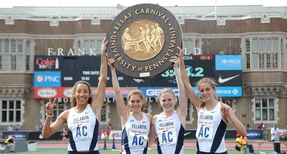 Events Varsity Sports Four female track and field athlets holding up Penn Relay medal