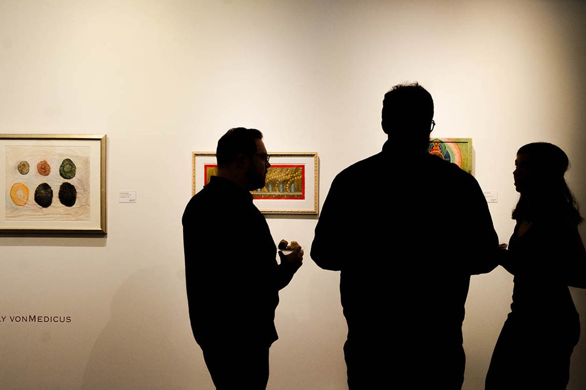 Three individual silhouettes standing in front of art pieces