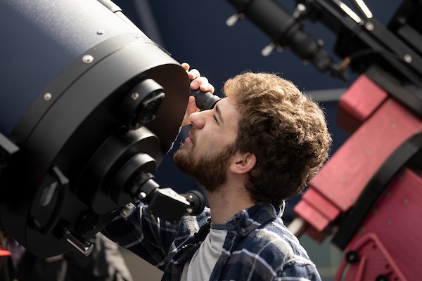 A student looks through a telescope in the observatory. A student looks through a telescope in the observatory.