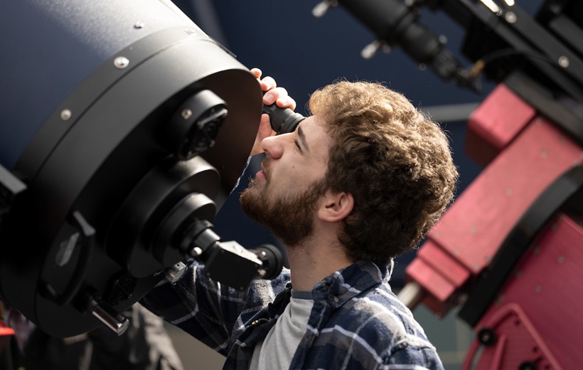 Student looks through a telescope in the observatory.