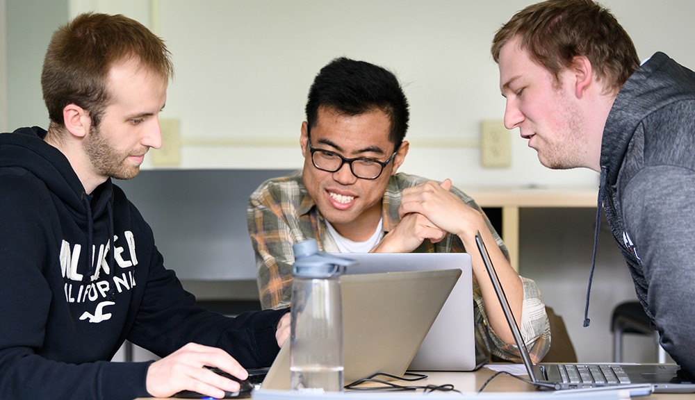 Graduate students seated at a table working on a group project Graduate students seated at a table working on a group project