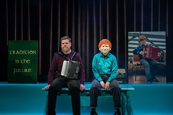 In a theatrical production of "Bellow," Danny O’Mahony sits with his accordion next to a marionette. Danny O’Mahony next to a marionette.