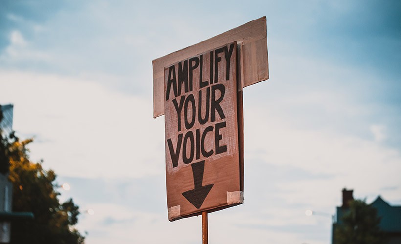 A sign that says, "Amplify your voice" A sign that says, "Amplify your voice"