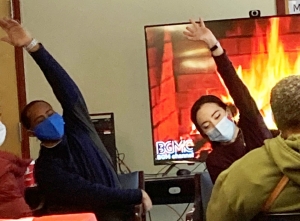 Students demonstrate yoga movements from a chair