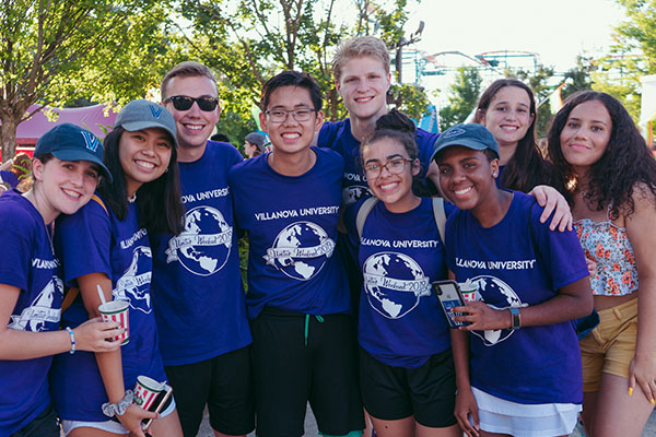 Students pose together outside, smiling in matching t-shirts.