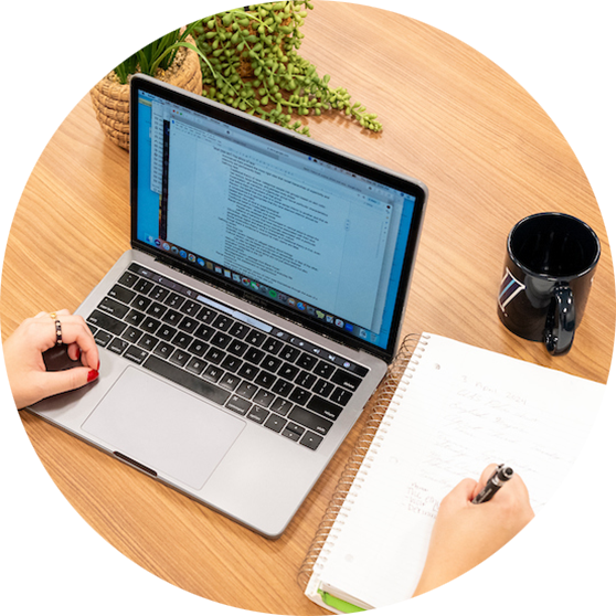 Person using a laptop and writing in a notebook