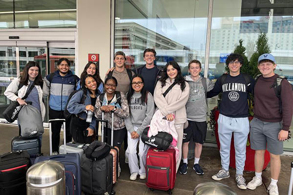 Students smiling with luggage outside airport