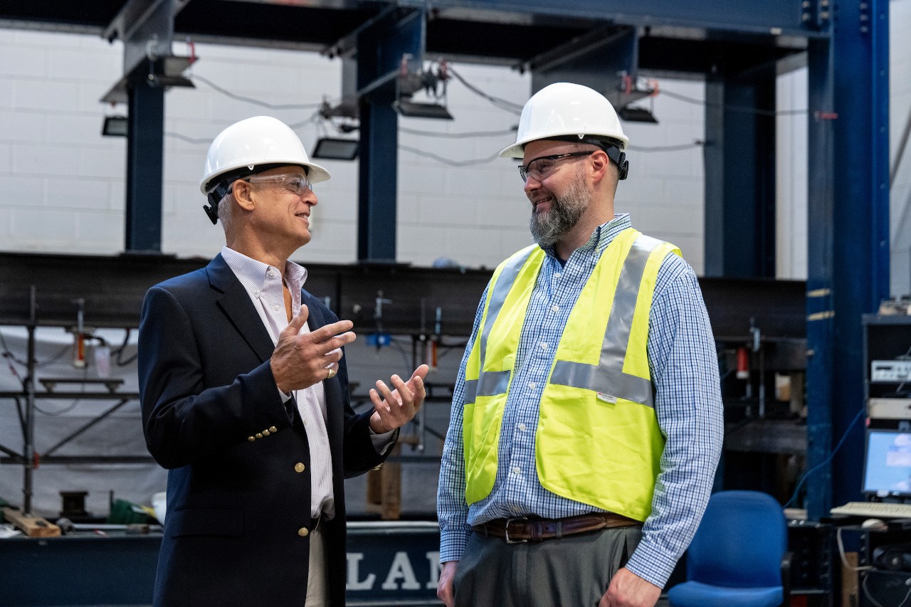 two men in hardhats talking in a warehouse