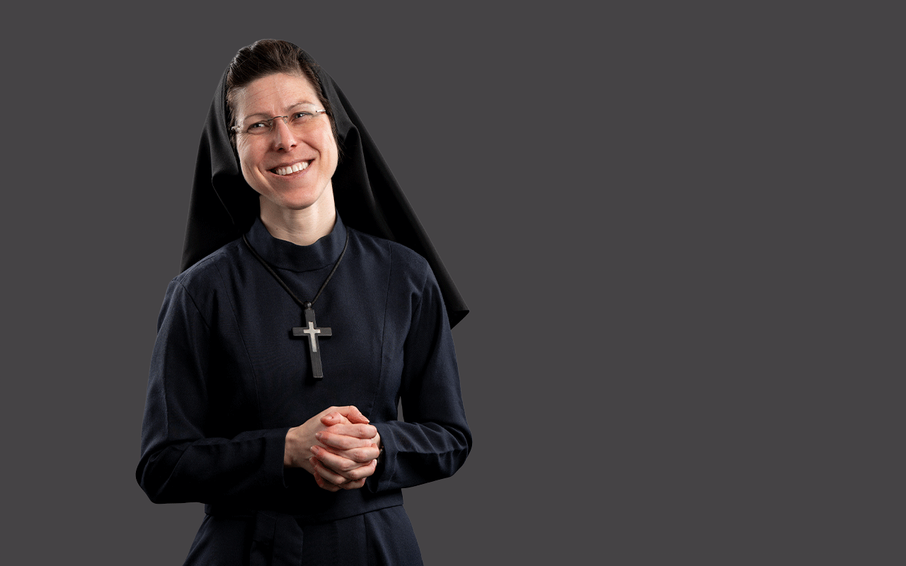 Sister Brigid Mary Meeks, RSM, in a standing pose with her hands clasped wearing her habit