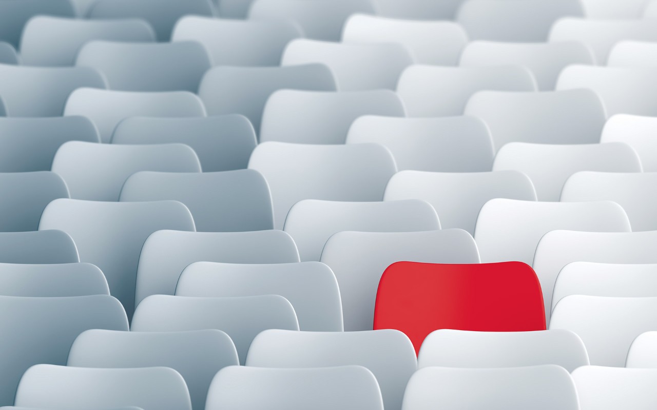 Rows of white chairs with a bright red chair