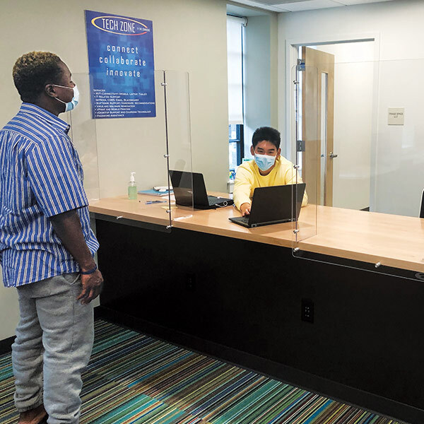 a man stands across from another man sitting at a desk